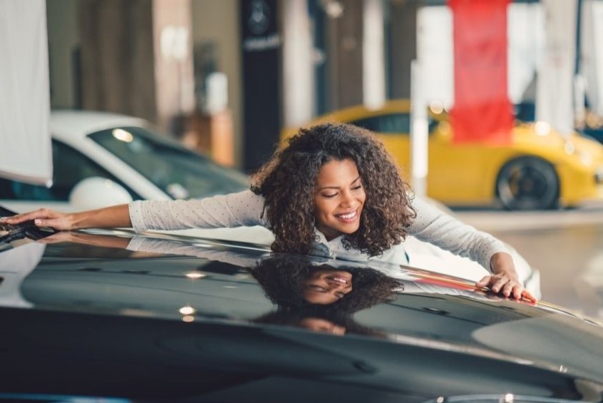 Woman hugging hood of new, black auto.